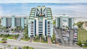 Un hôtel moderne à la façade symétrique, doté de plusieurs parkings et offrant une vue sur la plage.