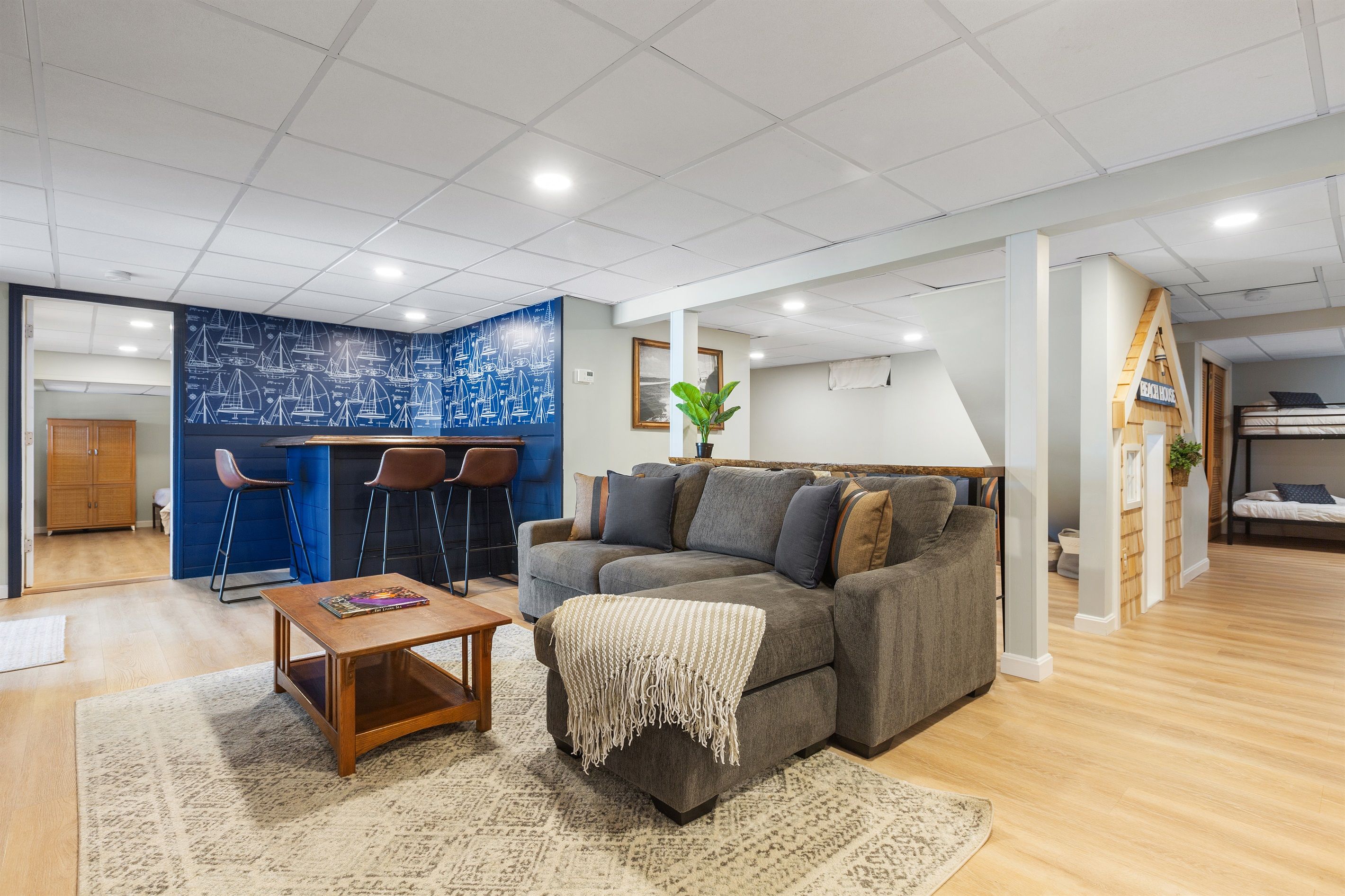 A modern living room with a grey sofa, a coffee table, and a blue accent wall with nautical designs.