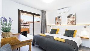 A modern hotel room with a bed, a desk, a chair, a potted plant, and a view of the outside. - Home2Book Modern Seaview Apt & Pool, Las Américas (Playa de la Américas)