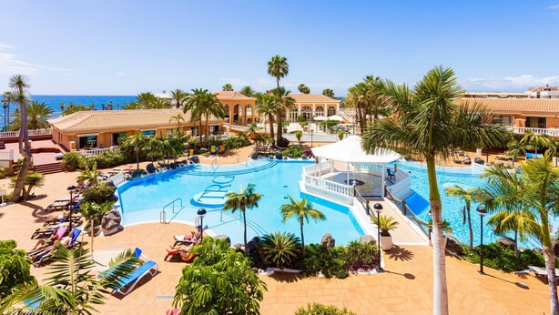 A resort with a large pool, palm trees, and a view of the ocean. - Home2Book Modern Seaview Apt & Pool, Las Américas (Playa de la Américas)