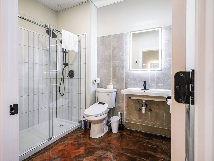 A modern bathroom with a glass shower enclosure, a toilet, a sink, and a mirror.