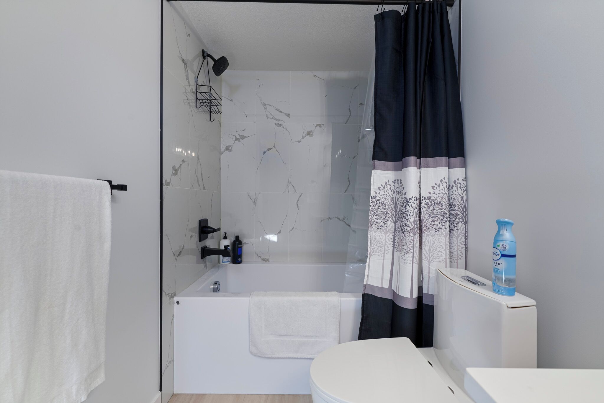 Een moderne badkamer met een bad, douche en toilet.