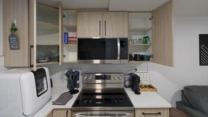 A compact kitchen with a built-in oven, microwave, and stainless steel stove. - Modern Suite Near Royal Alex Hospital, LRT, Rogers|Free WiFi, Parking & Netflix (Edmonton)