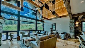 A spacious living room with large windows, a stone fireplace, and a cozy seating area. - Heaven`s Gate Luxury Ski-In/Out in Lewis Ranch (Copper Mountain)