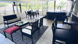 Ein überdachter Patio-Bereich mit Esstisch und Stühlen, einer Couch und einem gemusterten Teppich.