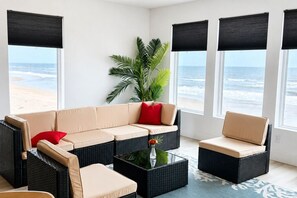 A room with a beige sectional sofa, a small black coffee table, and a potted plant. - Ocean Pearl Retreat - South Ponte Vedra Beach - Private Beach Access (Ponte Vedra Beach)