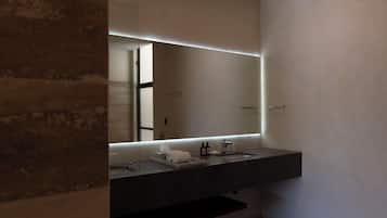 A modern bathroom with a dark countertop, a large mirror, and a towel rack.