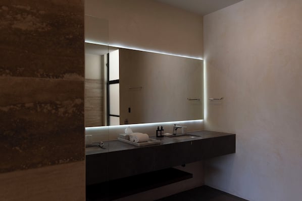 Un baño moderno con encimera oscura, un espejo grande y un perchero para toallas.