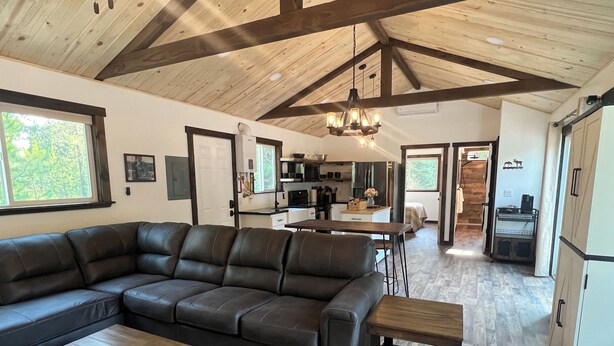 A spacious living area with a large sectional sofa, a wooden coffee table, and a kitchen in the background. - Cozy cabin in charming forested area (Spirit Lake)