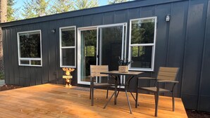 A modern building with a wooden deck, a table with chairs, and a decorative moose statue. - Cozy cabin in charming forested area (Spirit Lake)