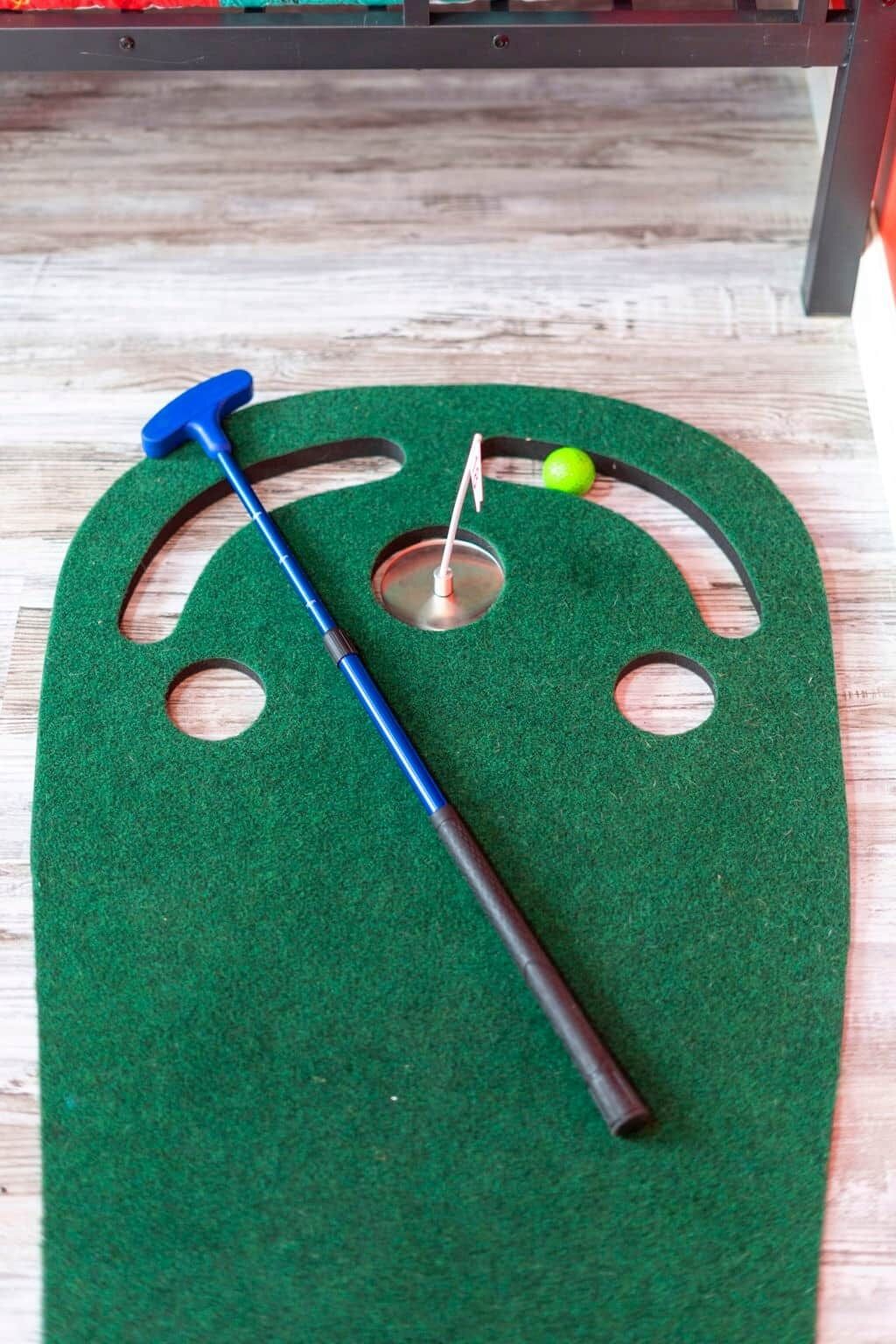 Groen kunstgras met een blauwe knuppel en een groene bal, waarschijnlijk voor een spel.