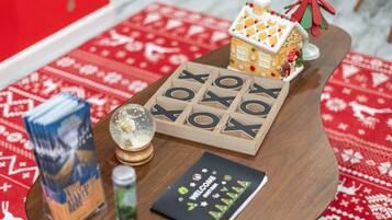 A wooden table with a wooden letter board spelling "WELCOME," a small gingerbread house, a snow globe, a box of milk, and a card with holiday decorations.