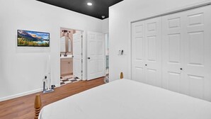 Une chambre à coucher avec un lit, une armoire blanche, une porte et un tableau accroché au mur.