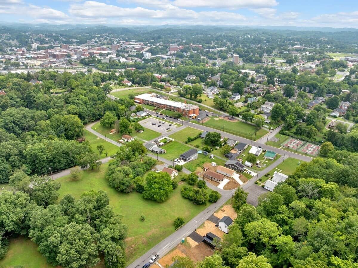 Vue aérienne d’un quartier résidentiel avec un grand ensemble d’immeubles, entouré de verdure et de maisons individuelles.