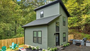 Ein zweistöckiges Haus mit einer Veranda, einer kleinen Terrasse und einem Whirlpool im Garten.