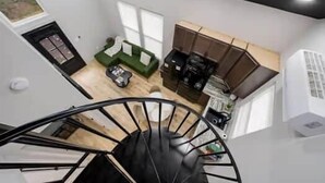Ein modernes Interieur mit einer Treppe, einem grünen Sofa, einer Kaffeemaschine und einer Küchenzeile.