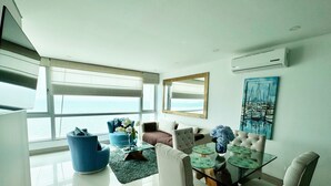 A modern living room with a large window, a painting, and a glass coffee table. - Exclusive apartment with sea view by Parceros Group (Cartagena de Indias)