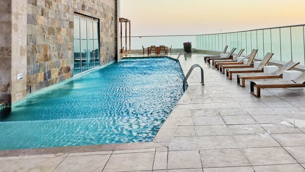 A rooftop pool with a stone wall and lounge chairs. - Exclusive apartment with sea view by Parceros Group (Cartagena de Indias)