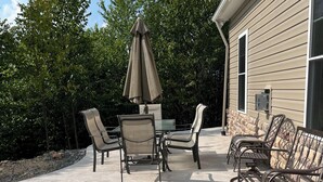 Een terras buiten met een tafel, stoelen, een parasol en een stenen muur.
