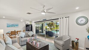 Un salón amplio con una gran mesa de centro, dos sofás, un televisor y un ventilador de techo.