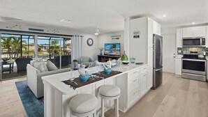 Una cocina moderna con gabinetes blancos, electrodomésticos de acero inoxidable y una isla grande con taburetes de bar.