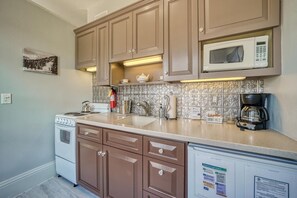 A kitchen with brown cabinets, a white stove, a microwave, and a coffee maker. - Downtown ~ Near River & Trails ~ Palace Hotel (Salida)