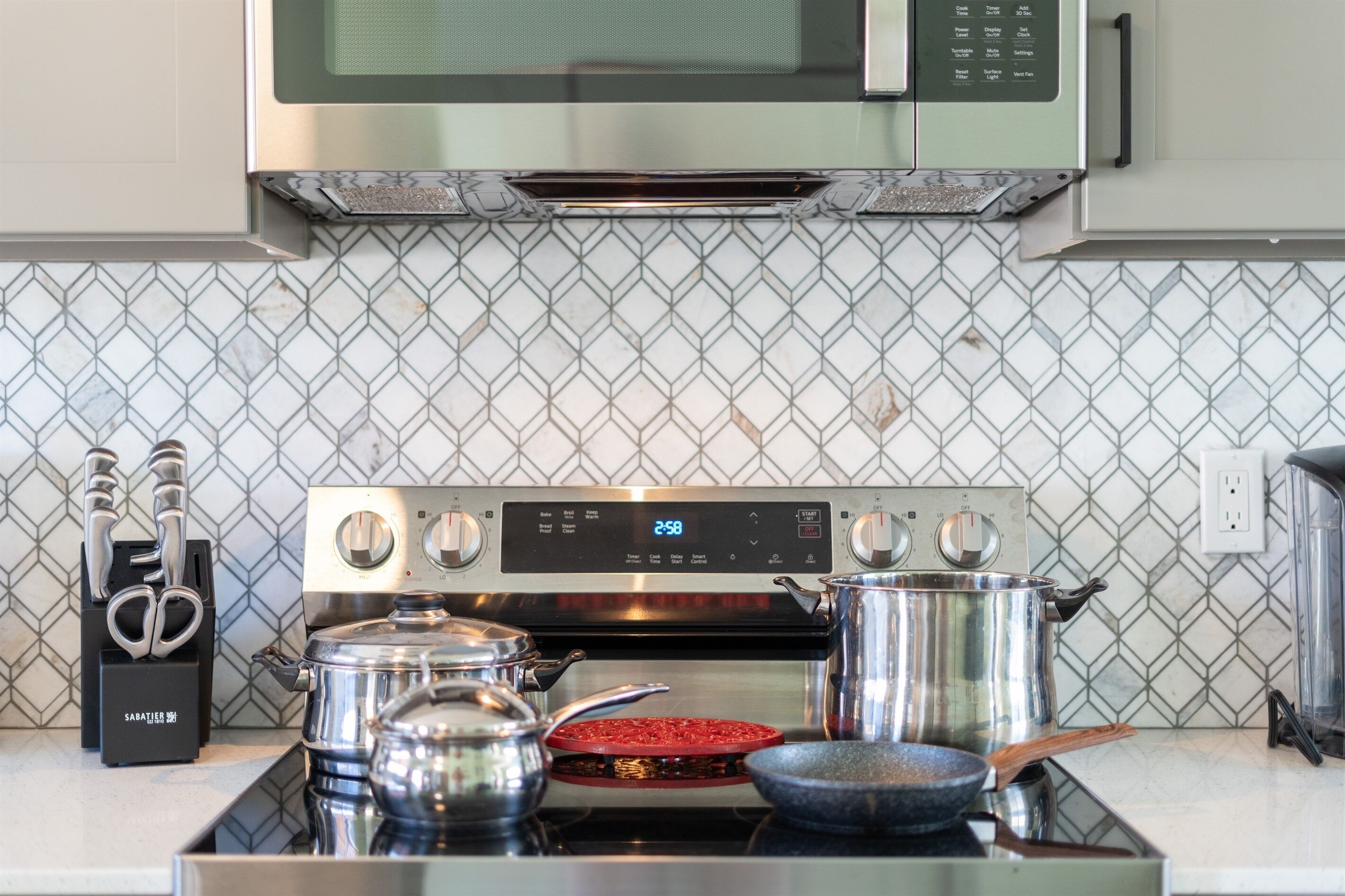 A kitchen with a microwave, stove, and various pots and pans.