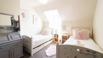 Een slaapkamer met twee eenpersoonsbedden, een dressoir, een spiegel en een klein bureau.