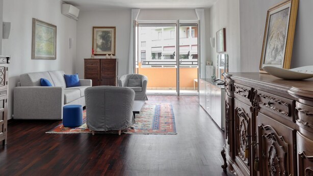 A living room with a sofa, armchair, and a wooden cabinet. - Iroko Living - Turro (Milano)