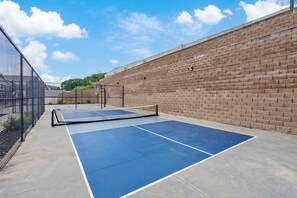 An outdoor tennis court with a net, surrounded by a brick wall and a metal fence. - Stunning Table Rock Lake Views with Free Tickets, Indoor & Outdoor Community Pools, Minutes to SDC (Branson)