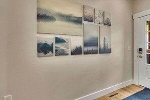 A hallway with a series of landscape paintings on the wall, a door, and a wooden floor. - Stunning Table Rock Lake Views with Free Tickets, Indoor & Outdoor Community Pools, Minutes to SDC (Branson)