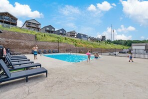A swimming pool area with lounge chairs, a pool ladder, and a grassy hill in the background. - Stunning Table Rock Lake Views with Free Tickets, Indoor & Outdoor Community Pools, Minutes to SDC (Branson)