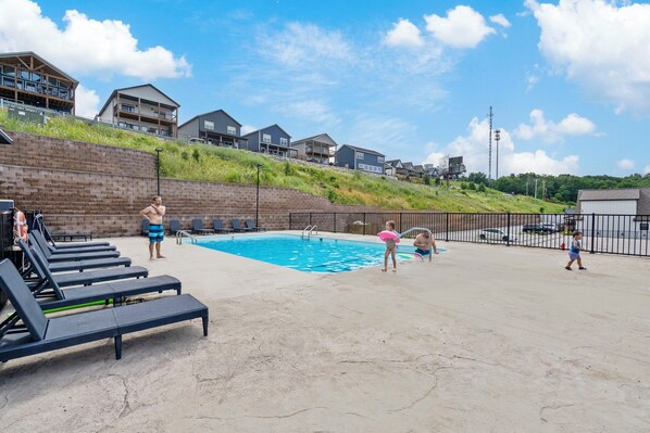A swimming pool area with lounge chairs, a pool ladder, and a grassy hill in the background. - Stunning Table Rock Lake Views with Free Tickets, Indoor & Outdoor Community Pools, Minutes to SDC (Branson)