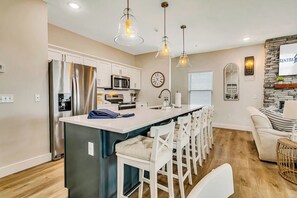 A modern kitchen with a central island, white bar stools, and pendant lighting. - Stunning Table Rock Lake Views with Free Tickets, Indoor & Outdoor Community Pools, Minutes to SDC (Branson)