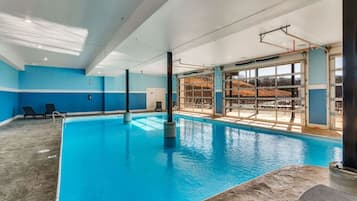 An indoor swimming pool with clear blue water, surrounded by blue walls and a large window.