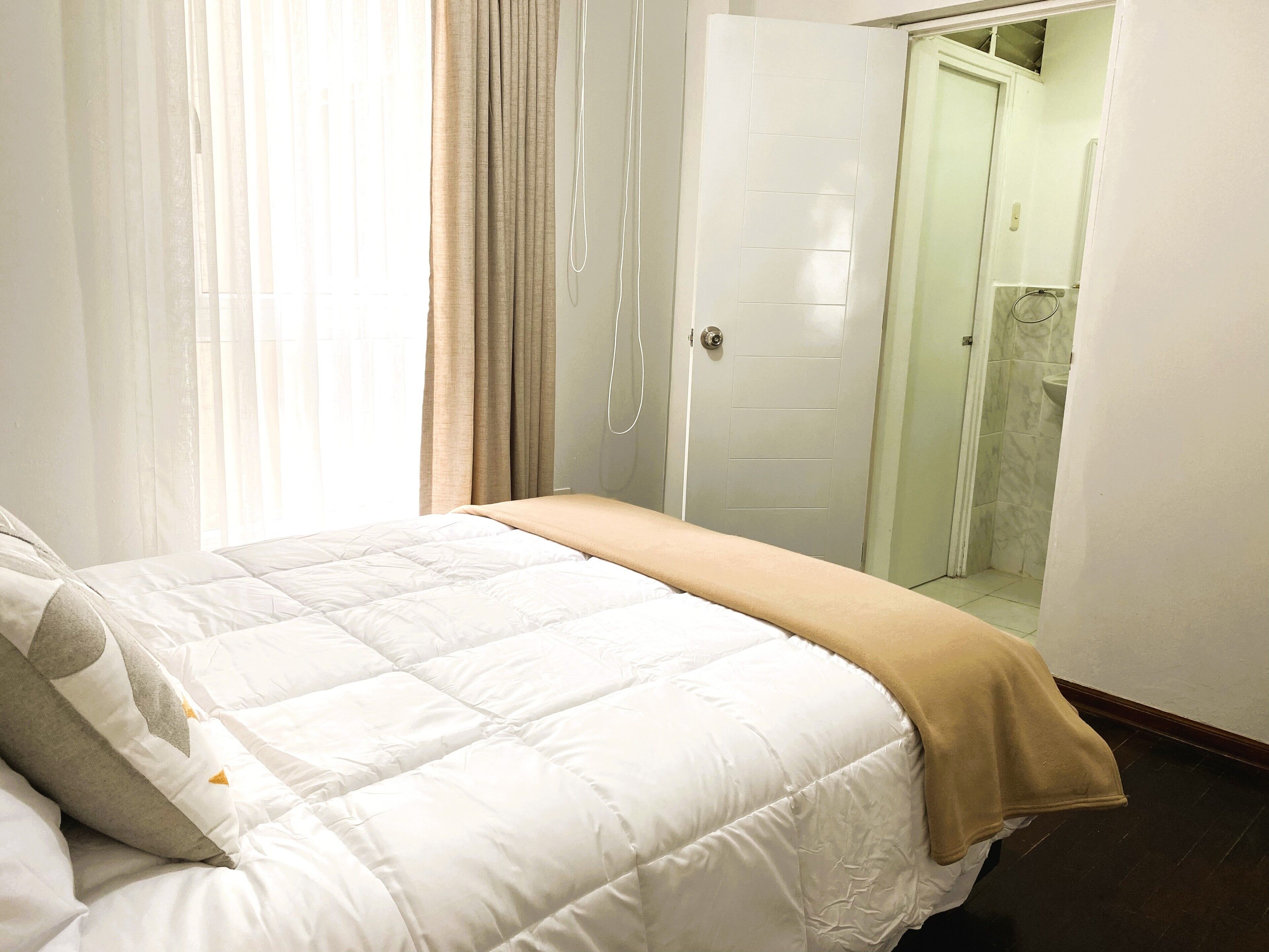 Un dormitorio con una cama, una puerta y un baño visible a través de una puerta abierta.