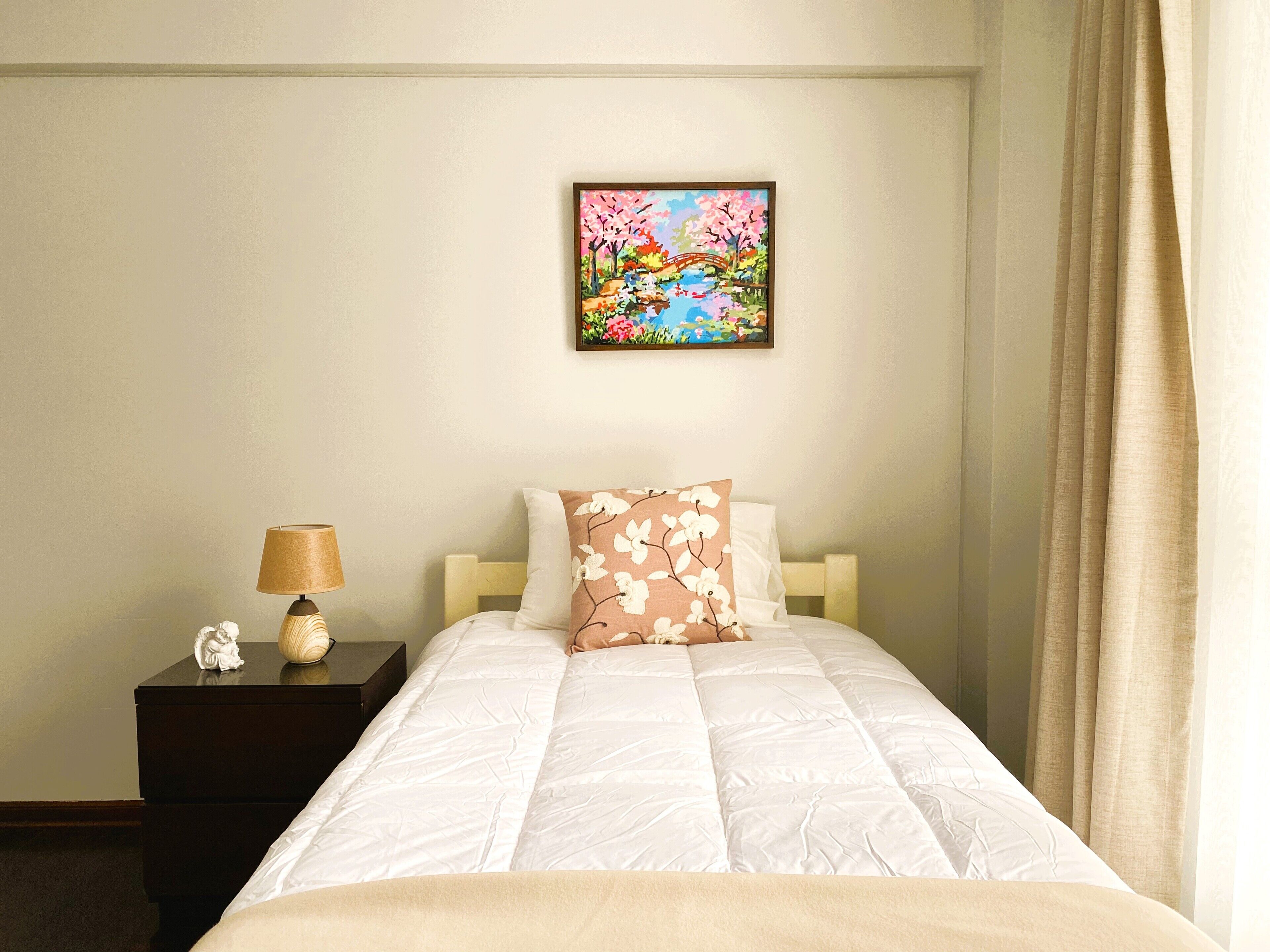 Une chambre d’hôtel avec un lit, une table de chevet avec une lampe, un objet décoratif et un tableau au mur.