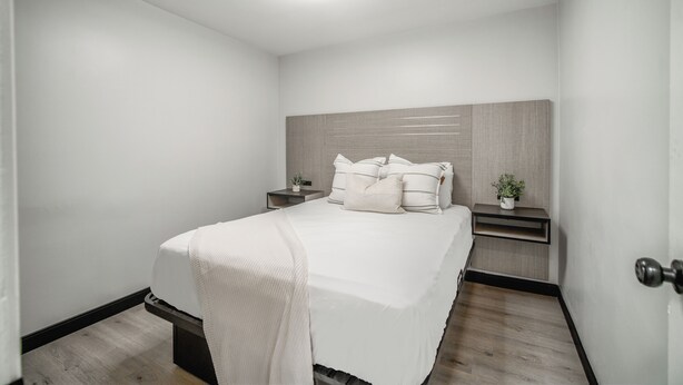 A modern bedroom with a large bed, bedside tables, a nightstand, and a ceiling light. - ERTH INN by AGA- San Ysidro (San Ysidro)