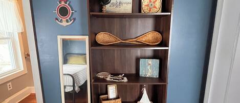 Ein Zimmer mit Holzboden, blauer Wand und einem dunklen Holzregal, das verschiedene Dekorationsgegenstände beherbergt.