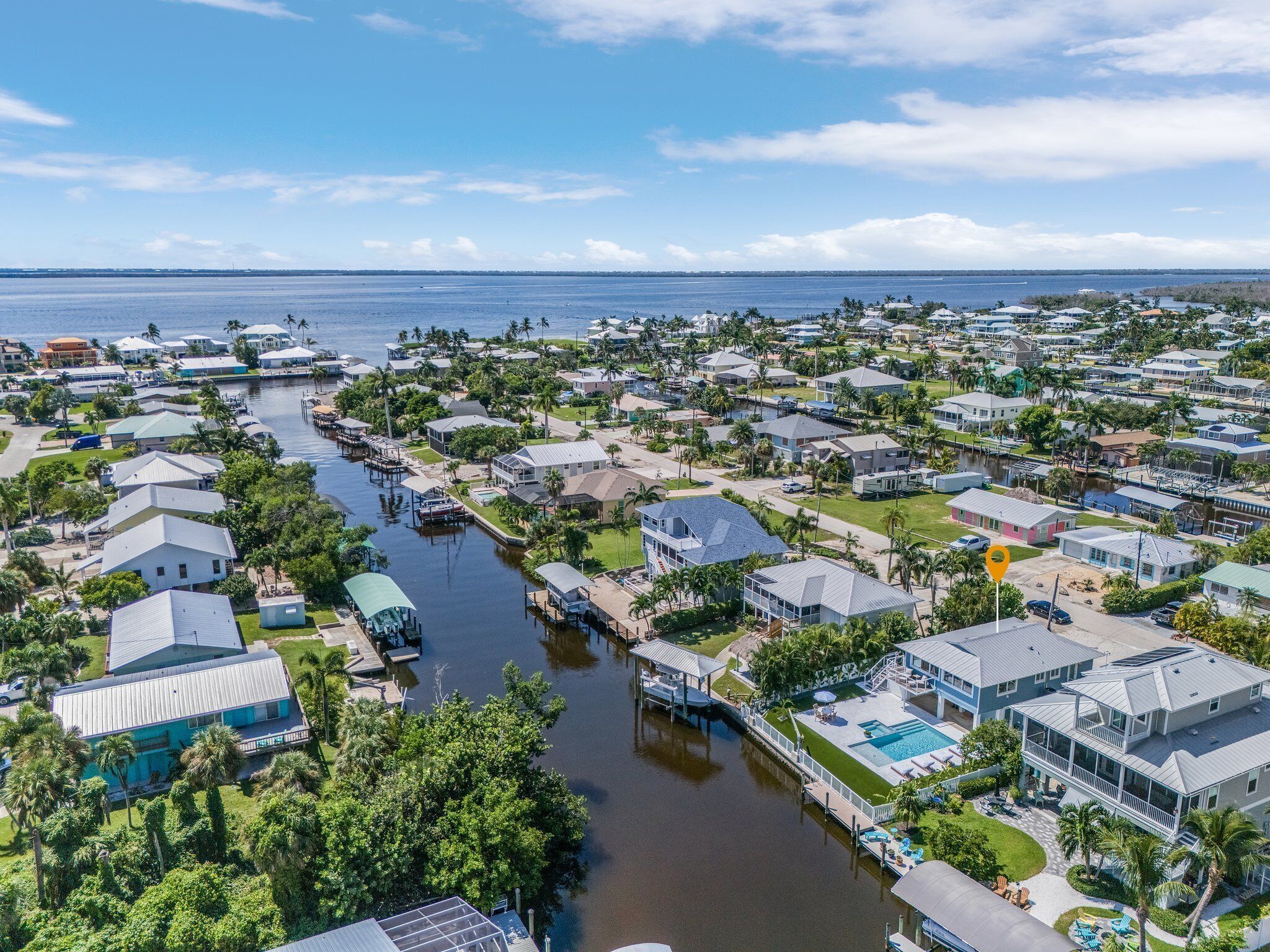 Luchtbeeld van een kustgebied met woonhuizen, een jachthaven en een groot wateroppervlak.