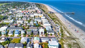 An aerial view of a coastal town with a beach, a pier, and a variety of residential buildings.
