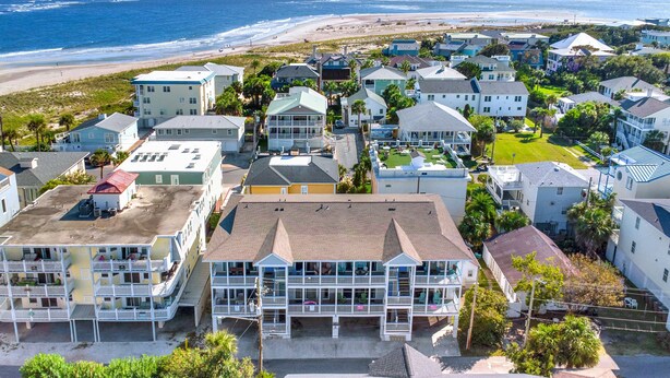 A coastal residential area with multiple two-story houses, some with balconies, and a beach in the background.