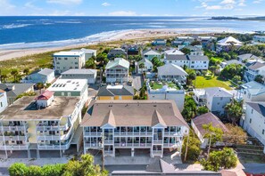A coastal residential area with multiple two-story houses, some with balconies, and a beach in the background.
