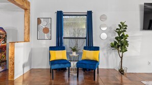 A room with two blue velvet chairs with yellow cushions, a small table, a potted plant, and a window with blue curtains. - 3 bed home with Luxury Hot Tub, Deck, Wifi and Arcade Games  (Houston)