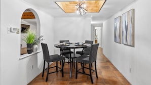 A dining area with a round table, six chairs, a potted plant, and a ceiling light fixture. - 3 bed home with Luxury Hot Tub, Deck, Wifi and Arcade Games  (Houston)