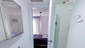 A bathroom with a granite sink, a mirror, and a shower area.