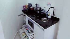 A compact kitchenette with a black countertop, a sink, and a small storage cabinet.