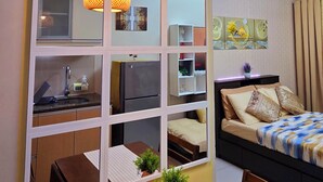 A compact living space with a kitchenette, a dining area, and a bed with decorative pillows. - 101 Newport Blvd: SkyStag Aerie - A cozy studio near NAIA Terminal 3 Airport (Pasay)