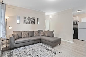 A modern living room with a grey sectional sofa, a patterned rug, and a minimalist decor.