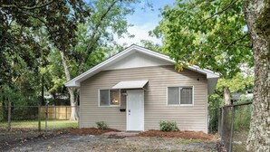Une maison de plain-pied avec une porte d’entrée, deux fenêtres et un petit porche.